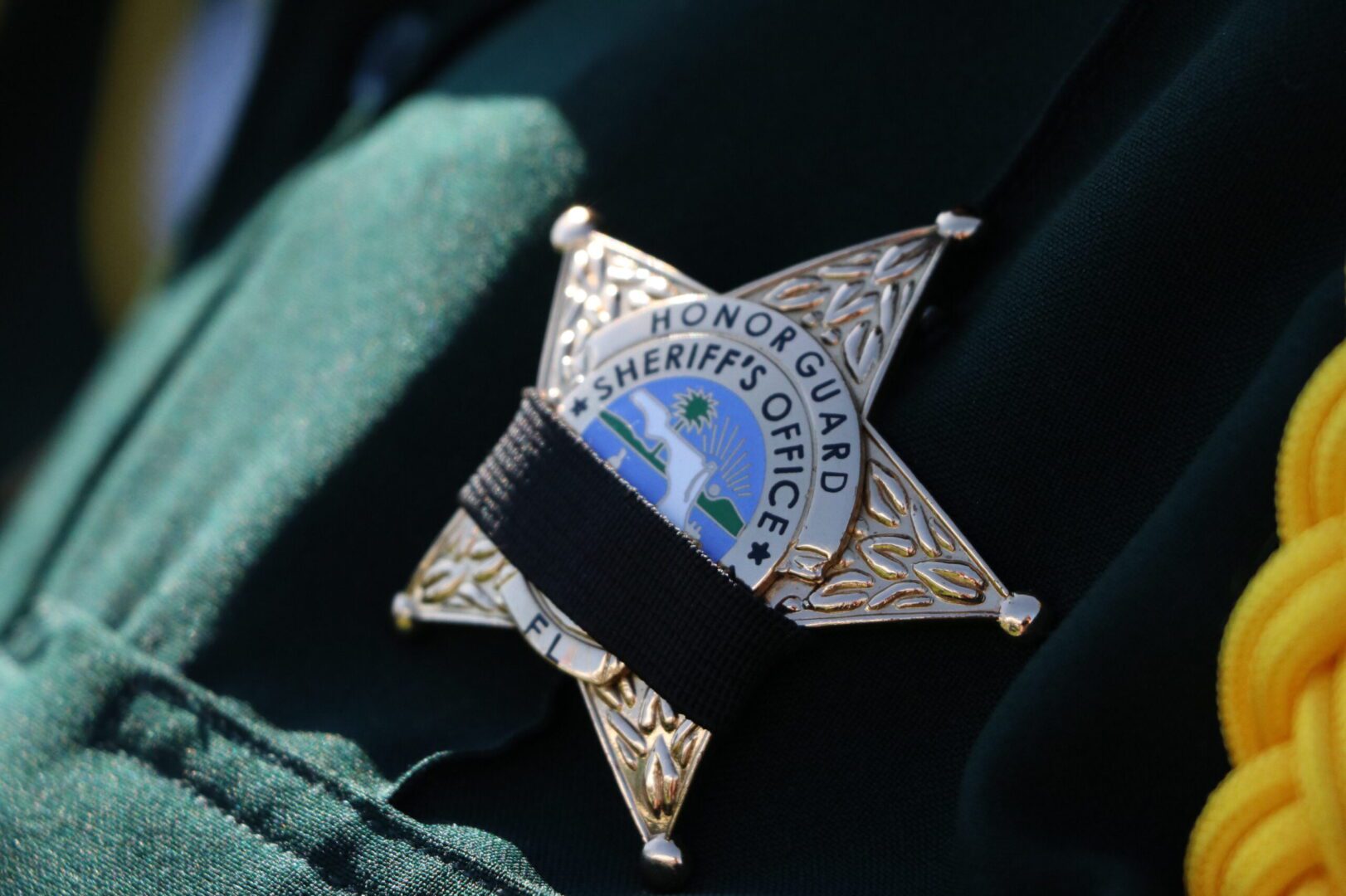 Close-up of a sheriff's badge on a green uniform with an inscription 