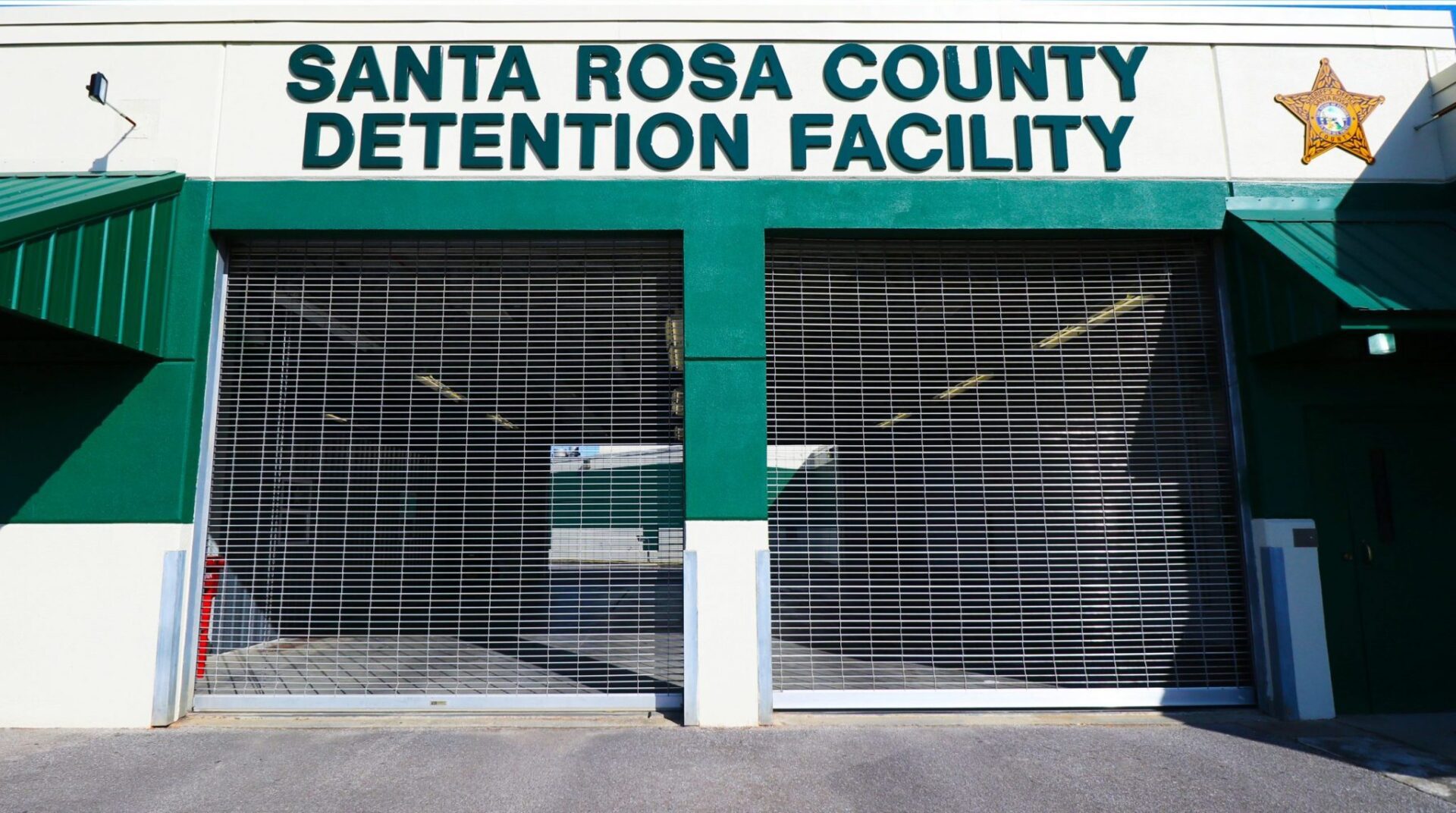 Entrance of the santa rosa county detention facility with green awnings and closed security gates.