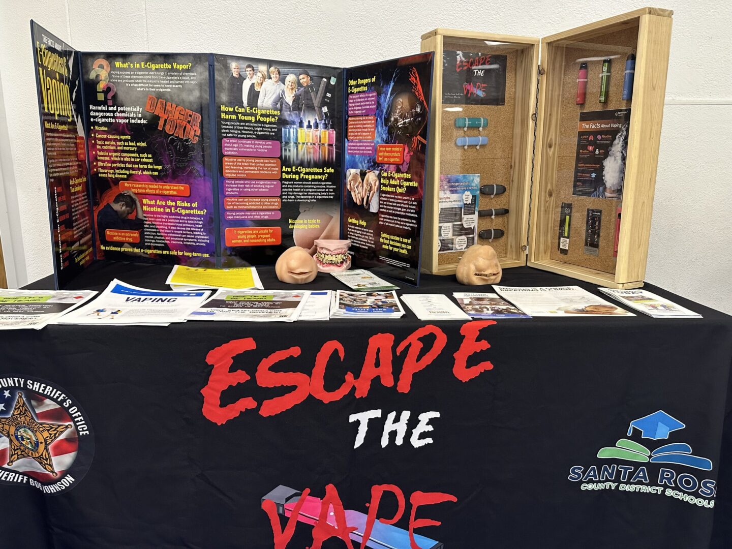 Informational booth titled "escape the vape" by santa rosa county sheriff's department, displaying educational materials and anti-vaping posters.