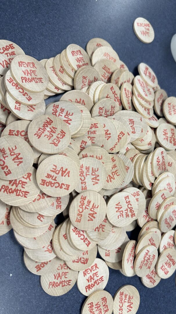 A pile of wooden tokens with "never never promise" stamped in red ink, scattered on a blue surface.